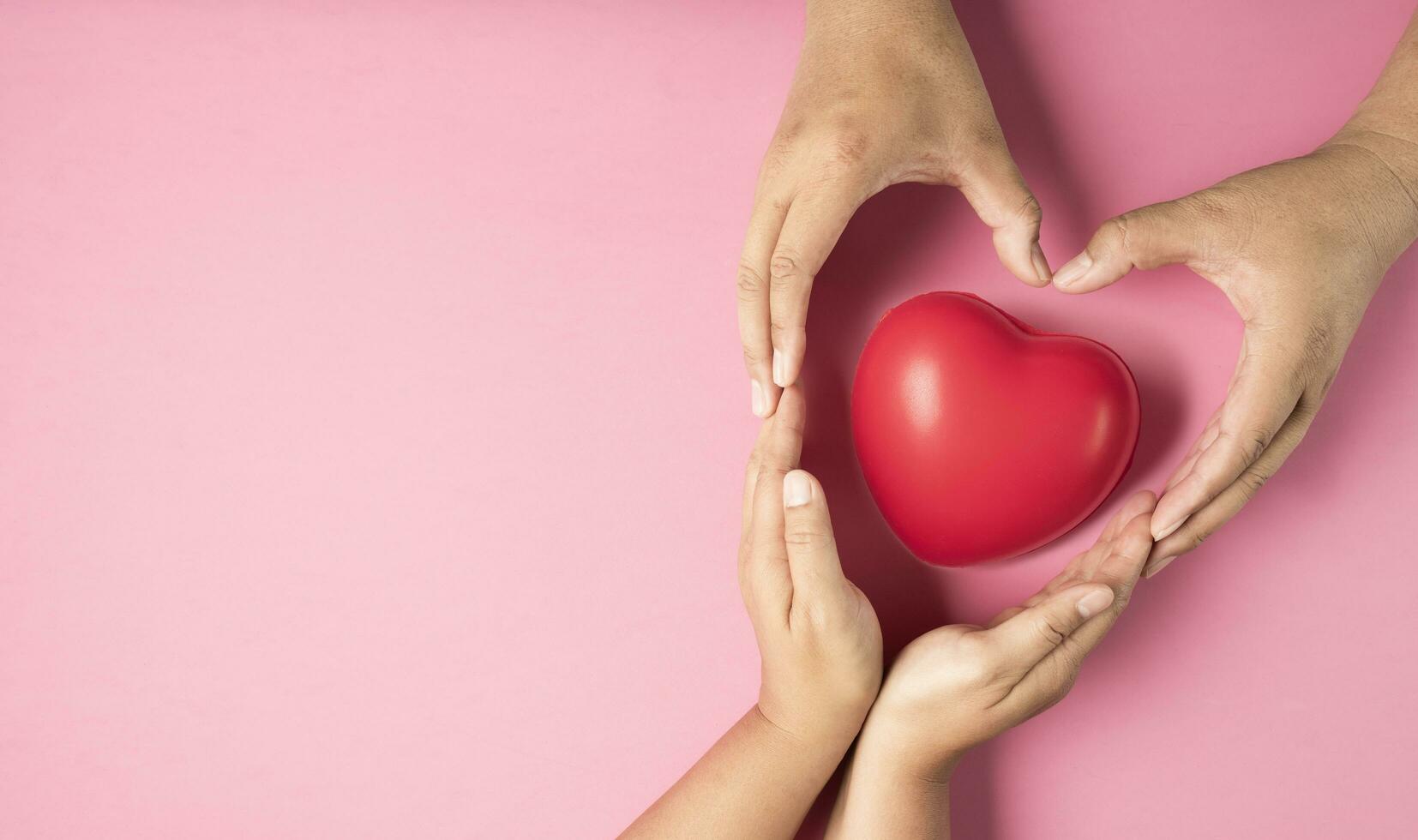 Adult hands made heart symbol on pink background , health care, organ donation, family life insurance, world heart day, world health day, praying concept photo