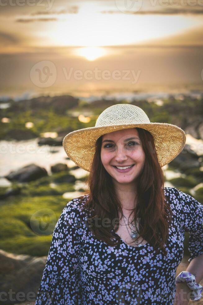mujer con sombrero disfrutar el puesta de sol a el rocoso playa en gaia, Oporto, Portugal. juni 17 2023. foto