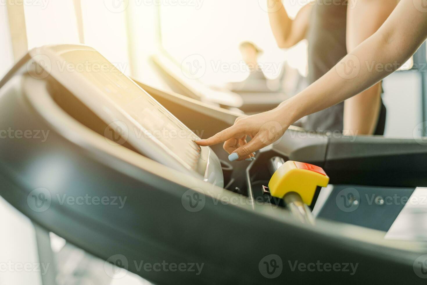 Healthy fitness girl running on treadmill sport club, closeup finger setting speed and climb level in control panel. photo