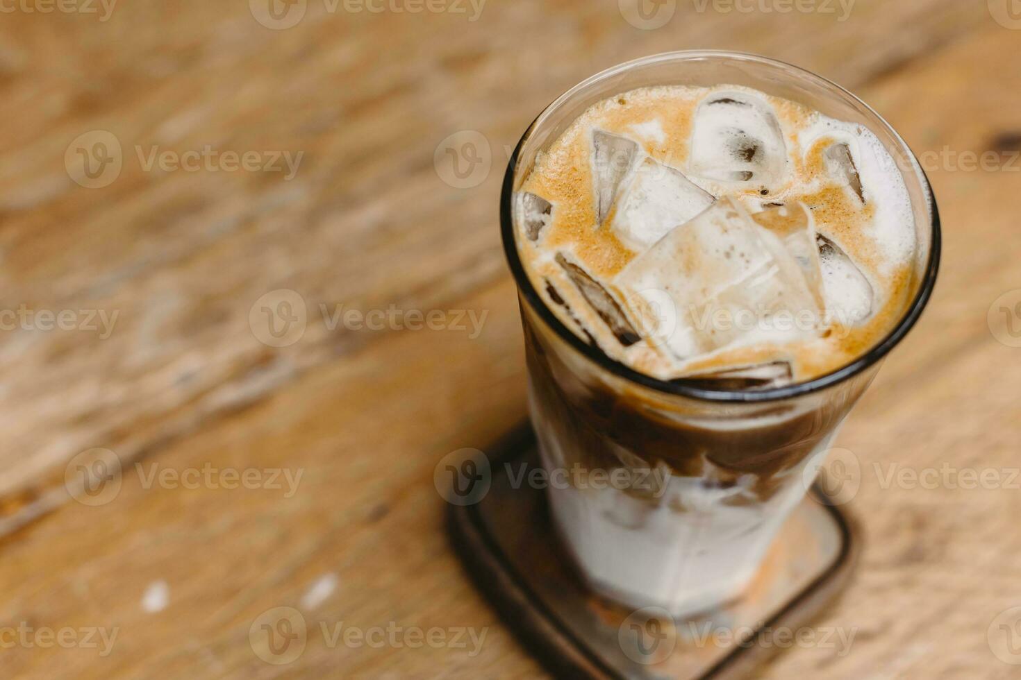 iced coffee, cold milk latte with ice on wood table background copy space for text photo