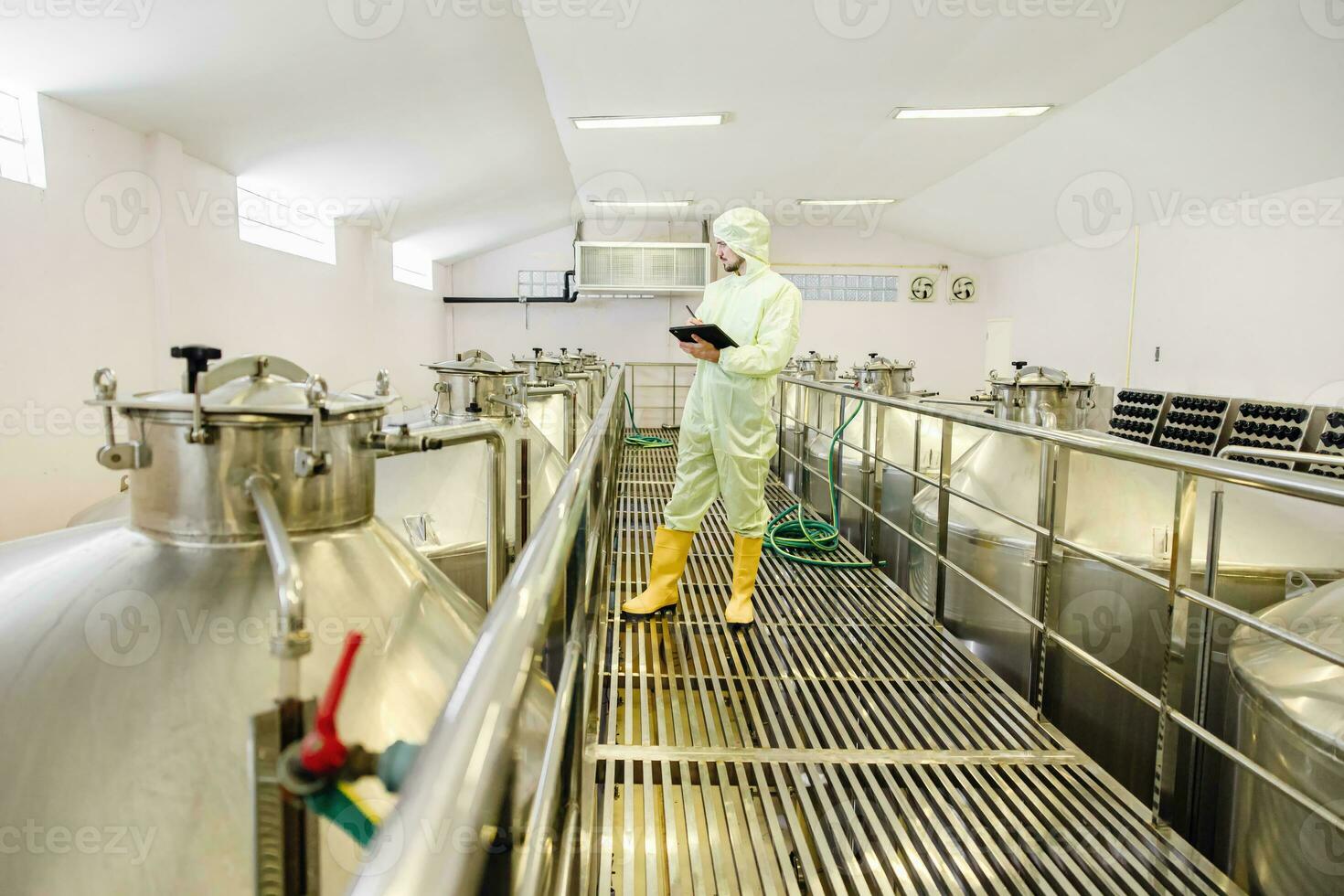 Brewery beverage factory worker working check fermentation tank with clean and hygiene cover suit. photo