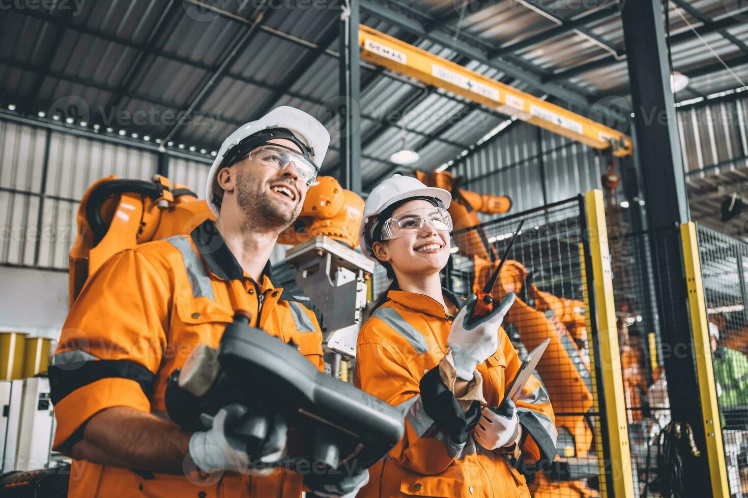 Engineer team working with robot welding in automation factory. People worker in safety suit control robotic arm in automated manufacturing industry technology. photo