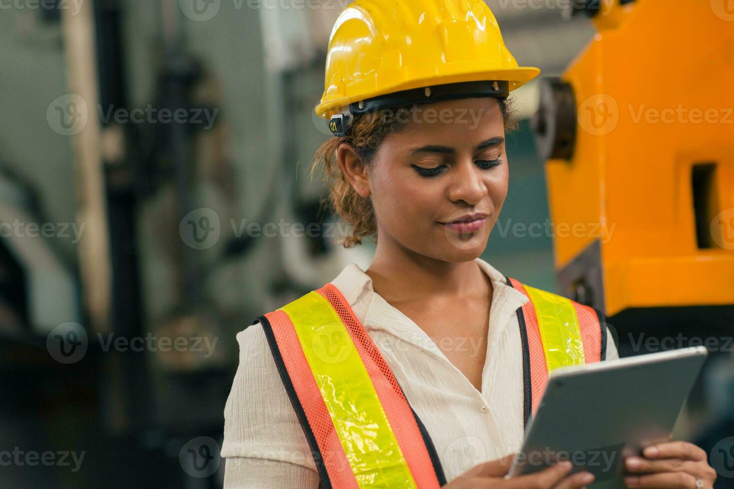 Happy African American Woman Engineer Worker Supervisor looking at Tablet computer to control operate maching in Heavy Industry Factory. photo