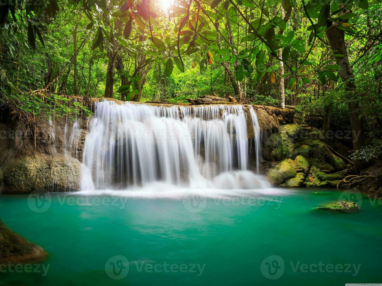 selva cascada fondo de pantalla, luz de sol brilla mediante el árboles, y hojas de un tropical bosque, y un cascada fluye dentro un azul agua estanque, cascada es oculto en el tropical selva, foto