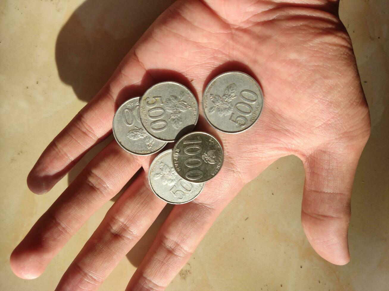 indonesio rupia monedas en mano con un valor de cinco cien rupias y uno mil rupias foto