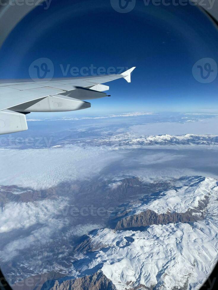 View from airplane window of snow-capped mountains in winter. photo