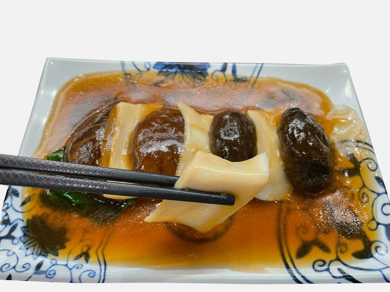 Chopsticks holding abalone with Stir Fried Hong Kong Kale. photo
