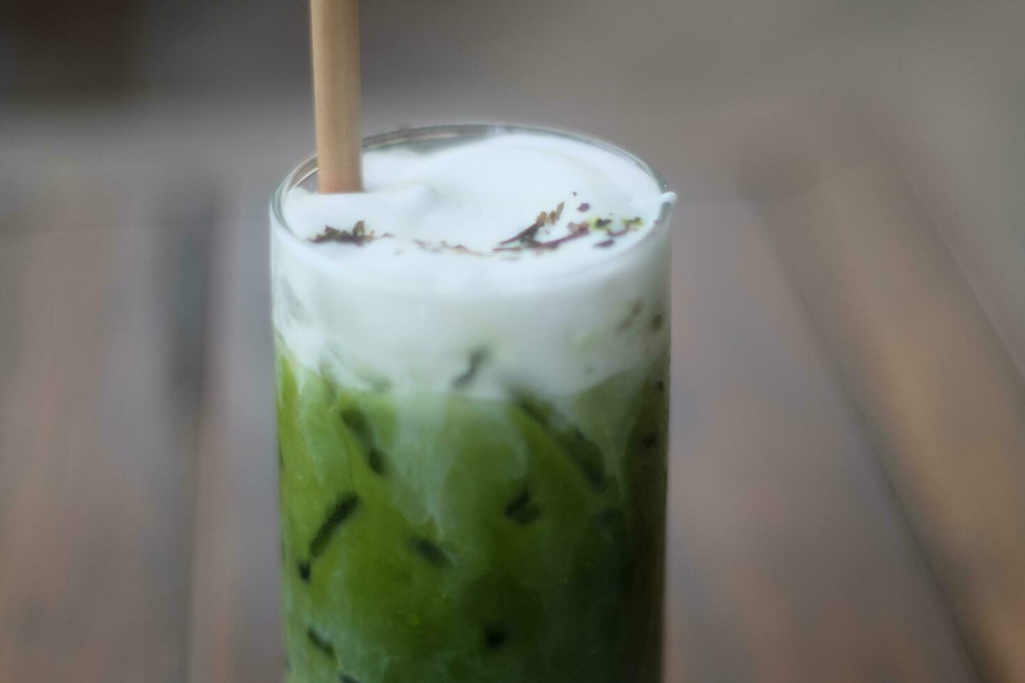 Iced matcha green tea latte in glass on wooden table photo