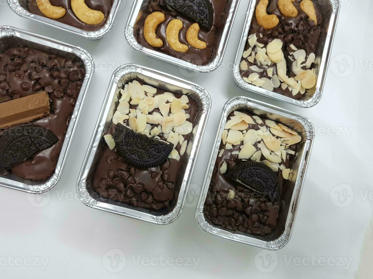 Chocolate cake brownie candies with nuts and chocolate chips in foil boxes. photo