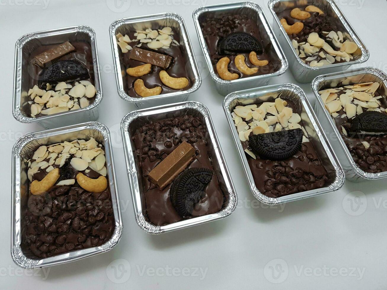 Chocolate cake brownie candies with nuts and chocolate chips in foil boxes. photo