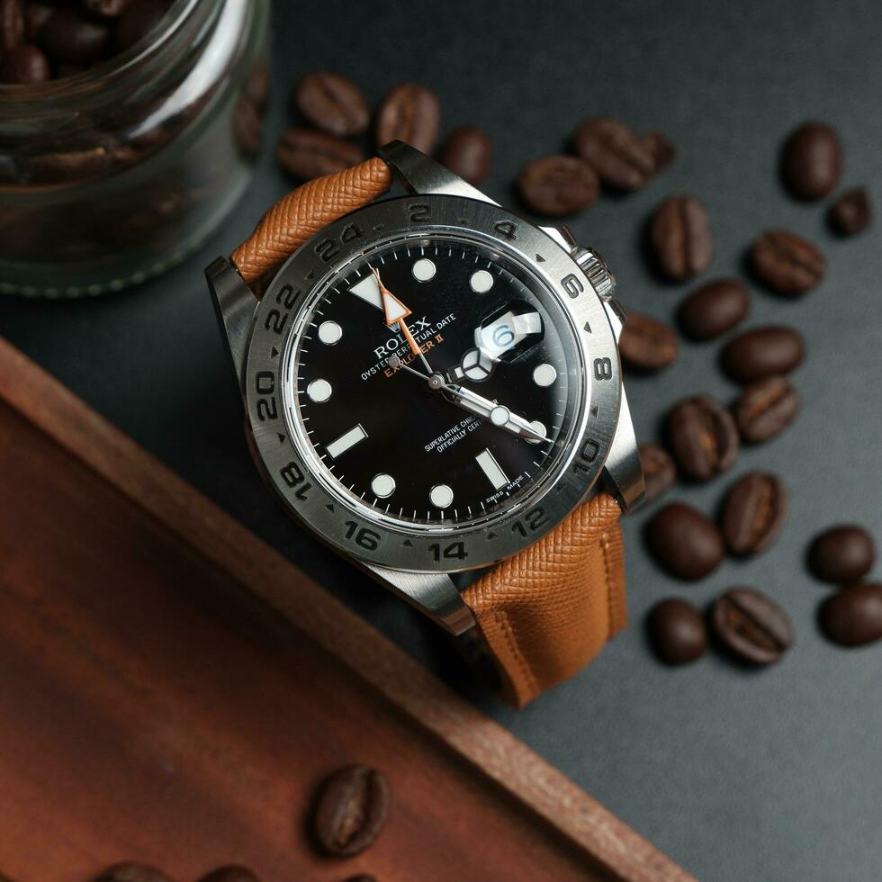 Surabaya, IDN, 2023 - product photo of a luxury watch with a light brown synthetic leather strap, against a dark background, wood chips and coffee beans