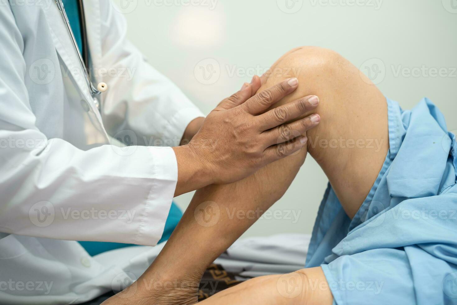 Asian doctor physiotherapist examining, massaging and treatment knee and leg of senior patient in orthopedist medical clinic nurse hospital. photo