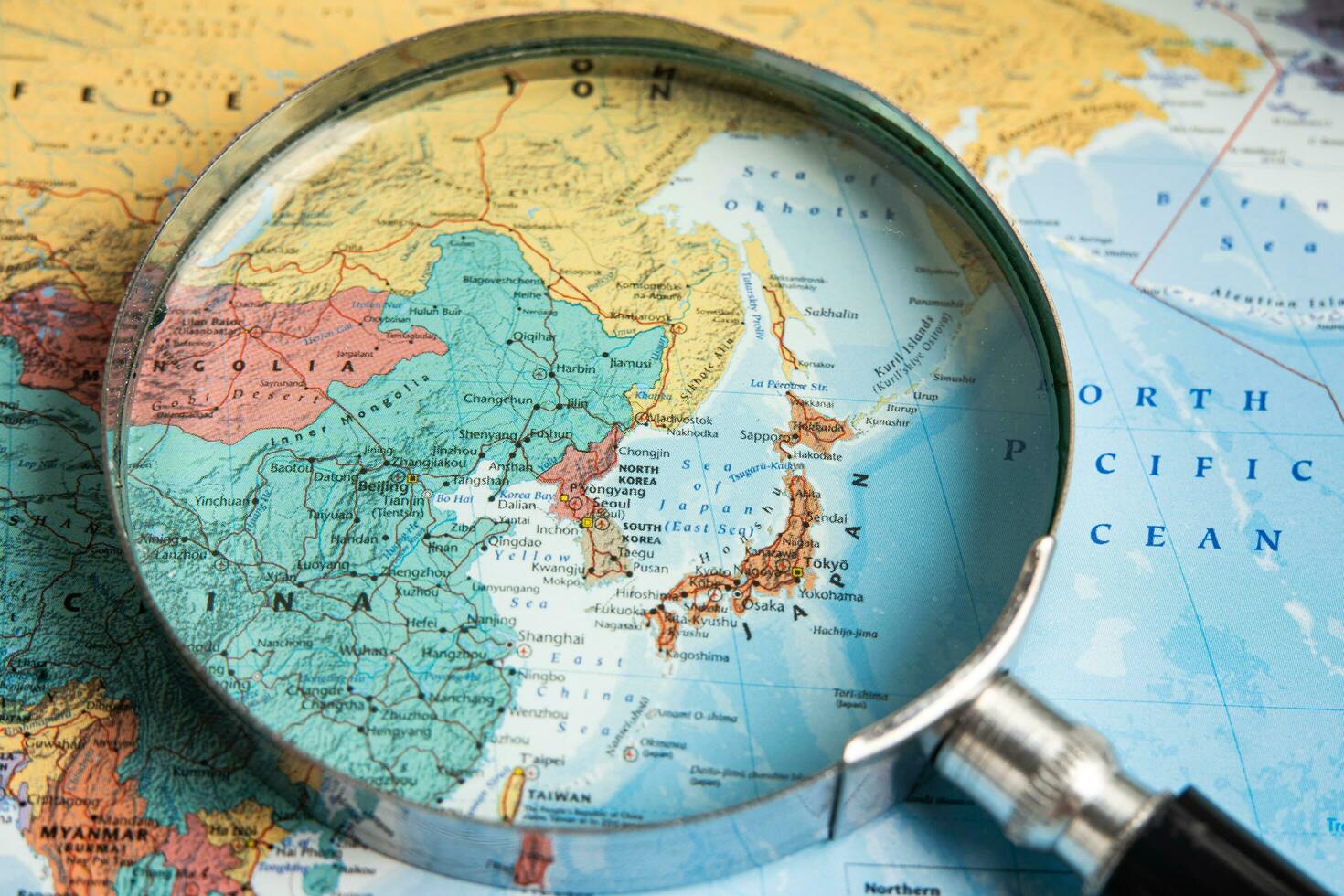 Bangkok, Thailand - January 20, 2022 Japan, Magnifying glass close up with colorful world map, travel, geography, tourism and exploration concept. photo