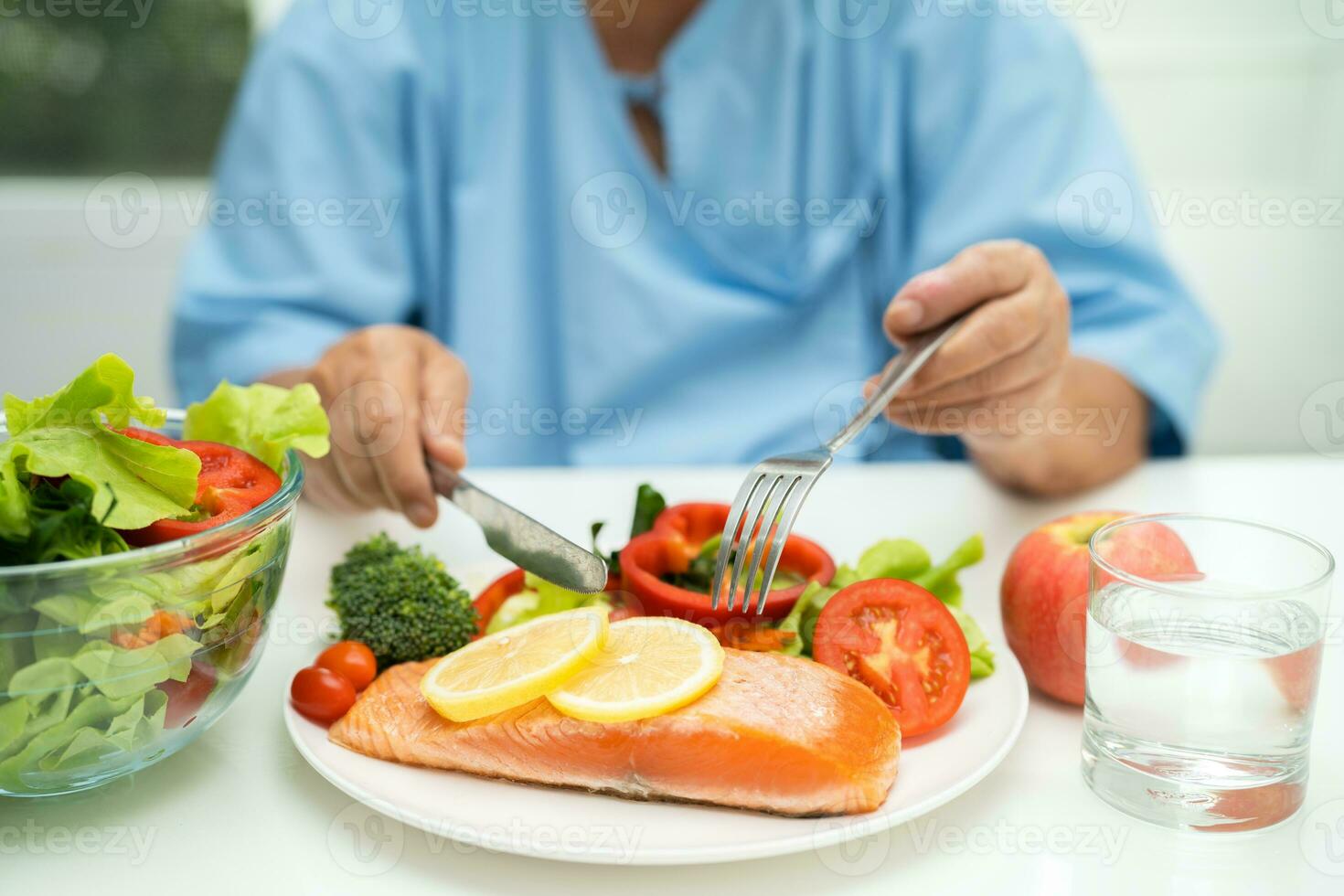 Asian elderly woman patient eating salmon steak breakfast with vegetable healthy food in hospital. photo