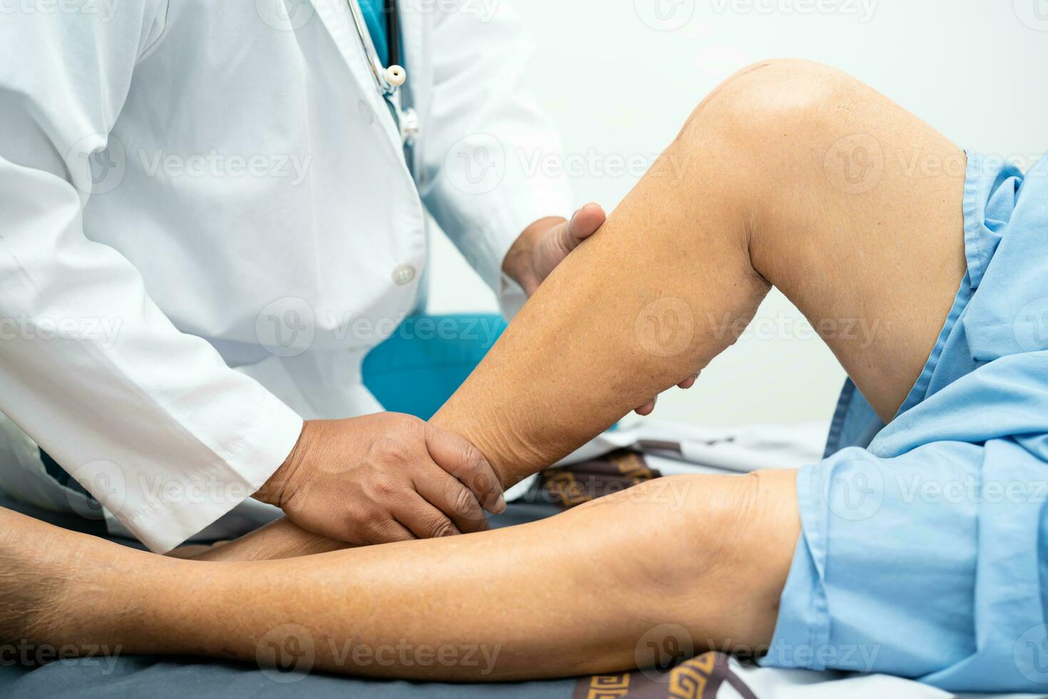 Asian doctor physiotherapist examining, massaging and treatment knee and leg of senior patient in orthopedist medical clinic nurse hospital. photo