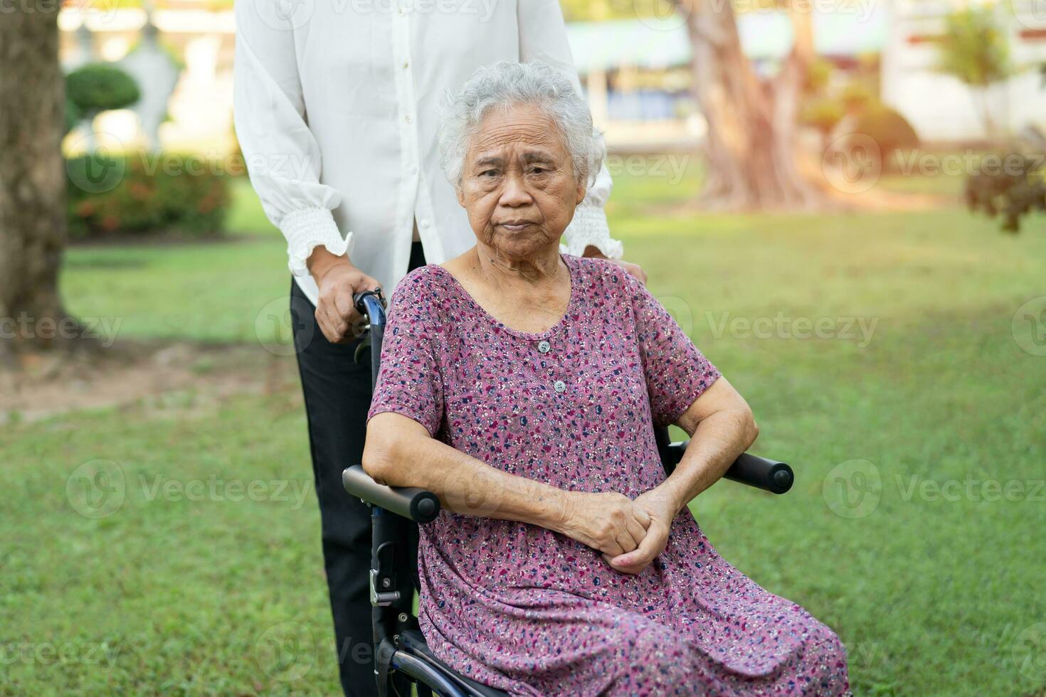 Caregiver help and care Asian elderly woman use walker with strong health while walking at park in happy fresh holiday. photo