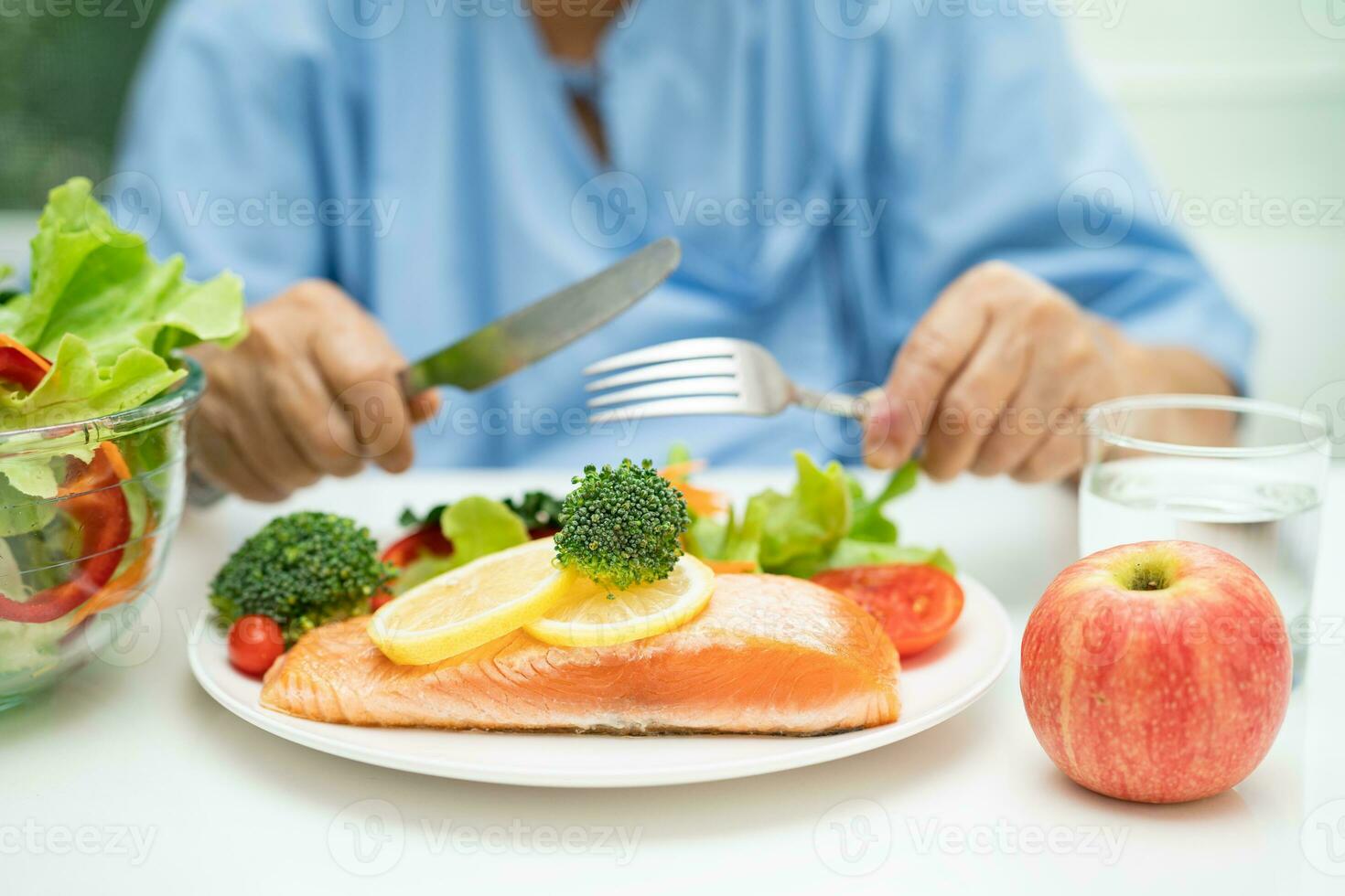 Asian elderly woman patient eating salmon steak breakfast with vegetable healthy food in hospital. photo