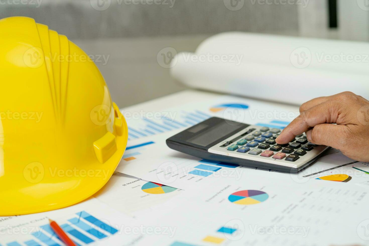 Asian engineer with architectural house plan project blueprint, graph and yellow helmet and engineering construction tools. photo