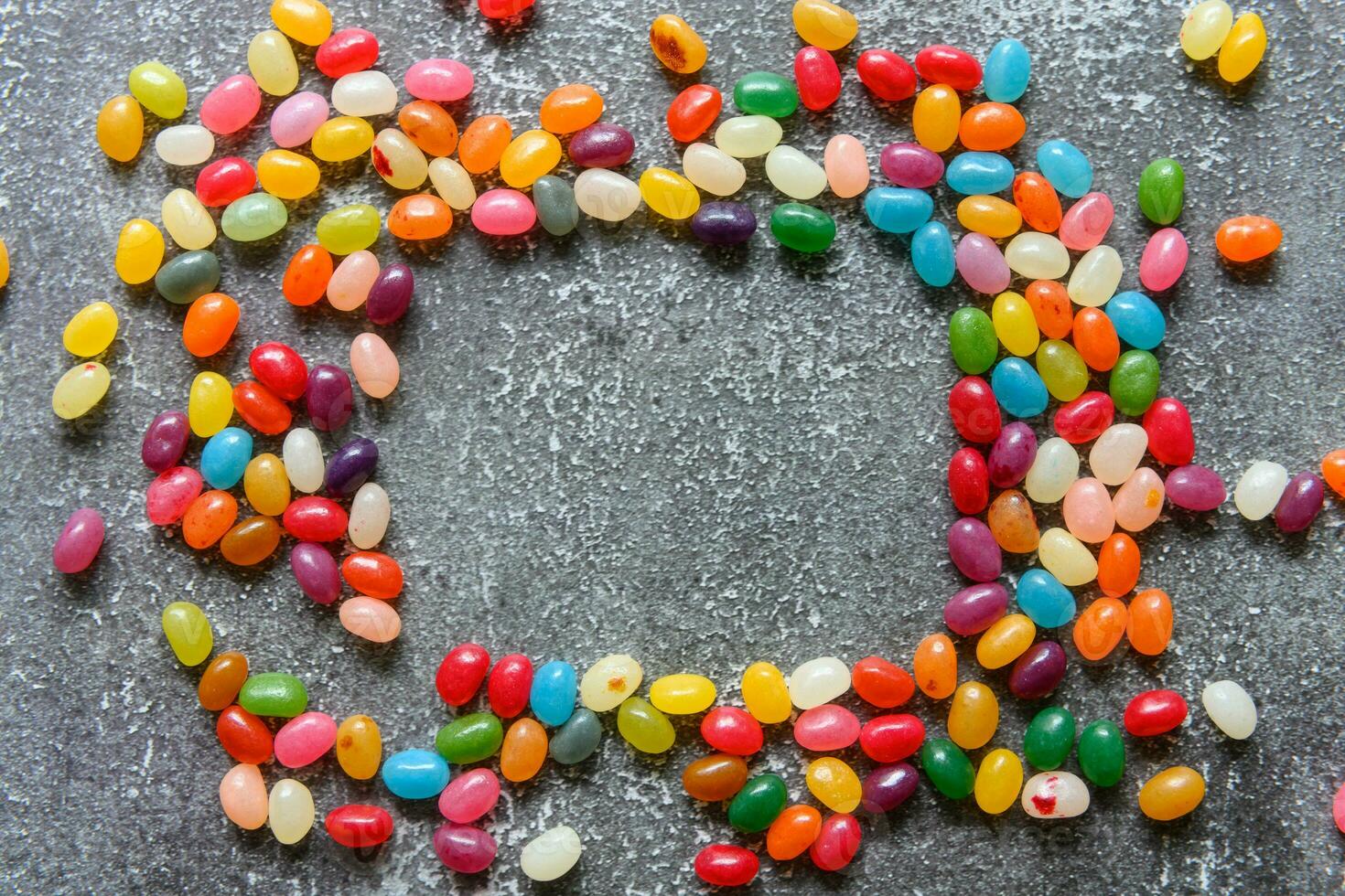 Frame of colorful jellybeans on rustic grey background with copy space photo