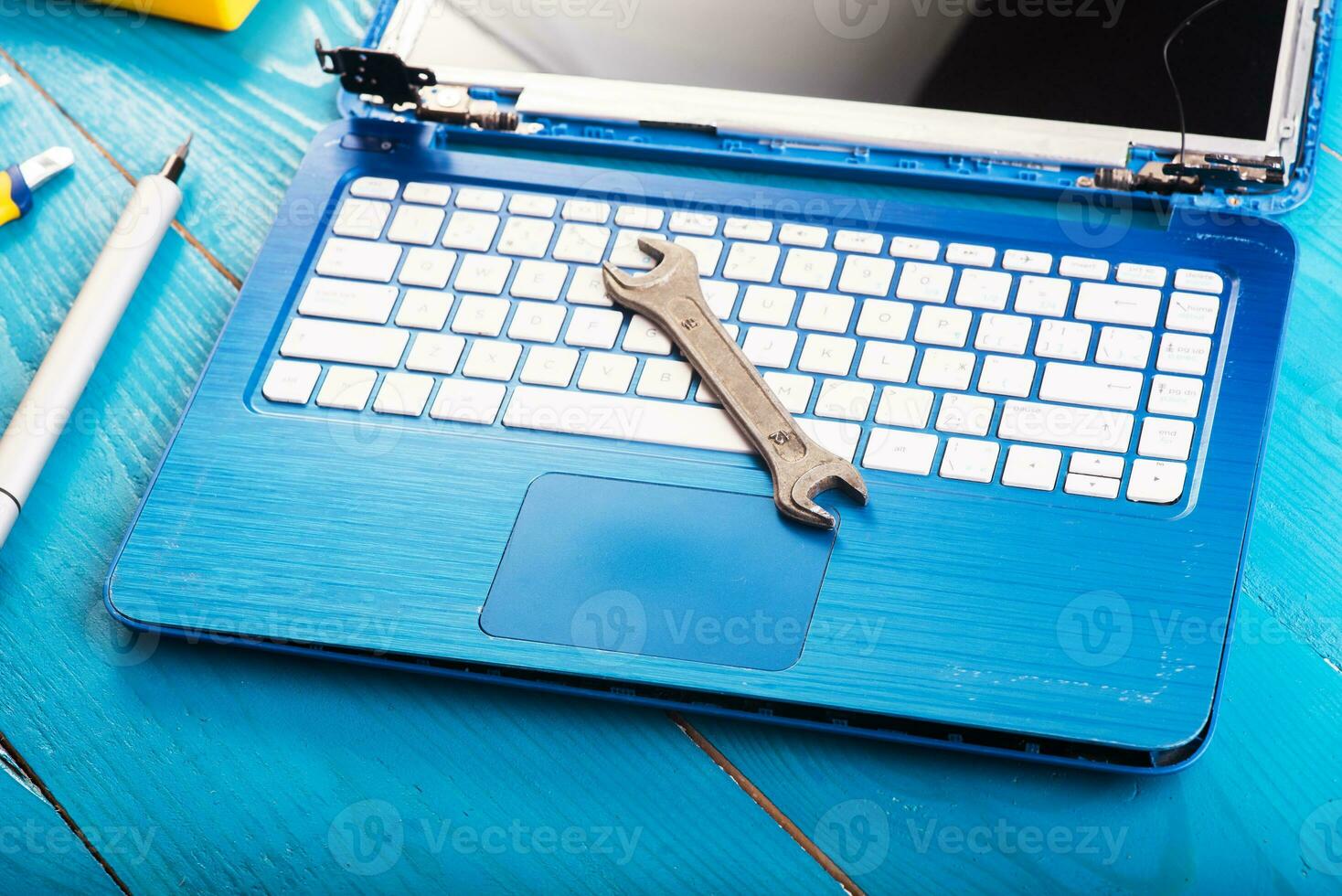 Wizard repairs laptop with tools and hands on the blue wooding table. top view photo