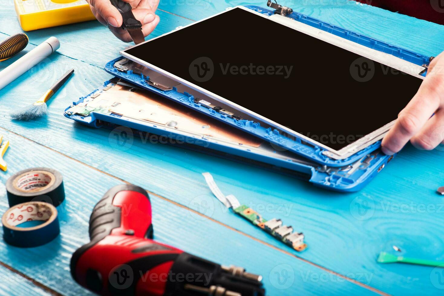 Wizard repairs laptop with tools and hands on the blue wooding table. top view photo