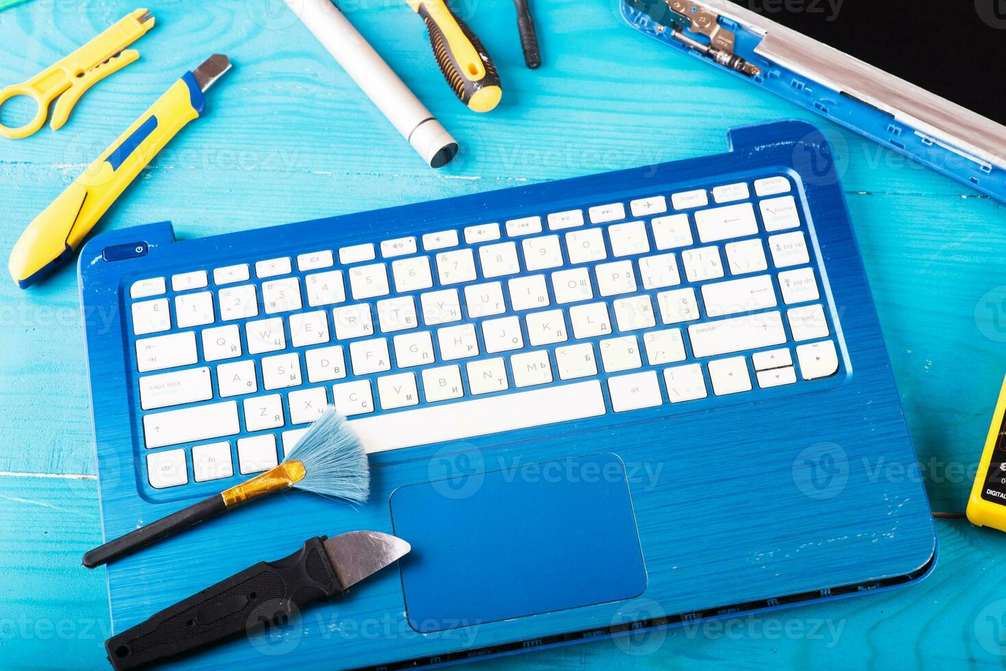 Wizard repairs laptop with tools and hands on the blue wooding table. top view photo