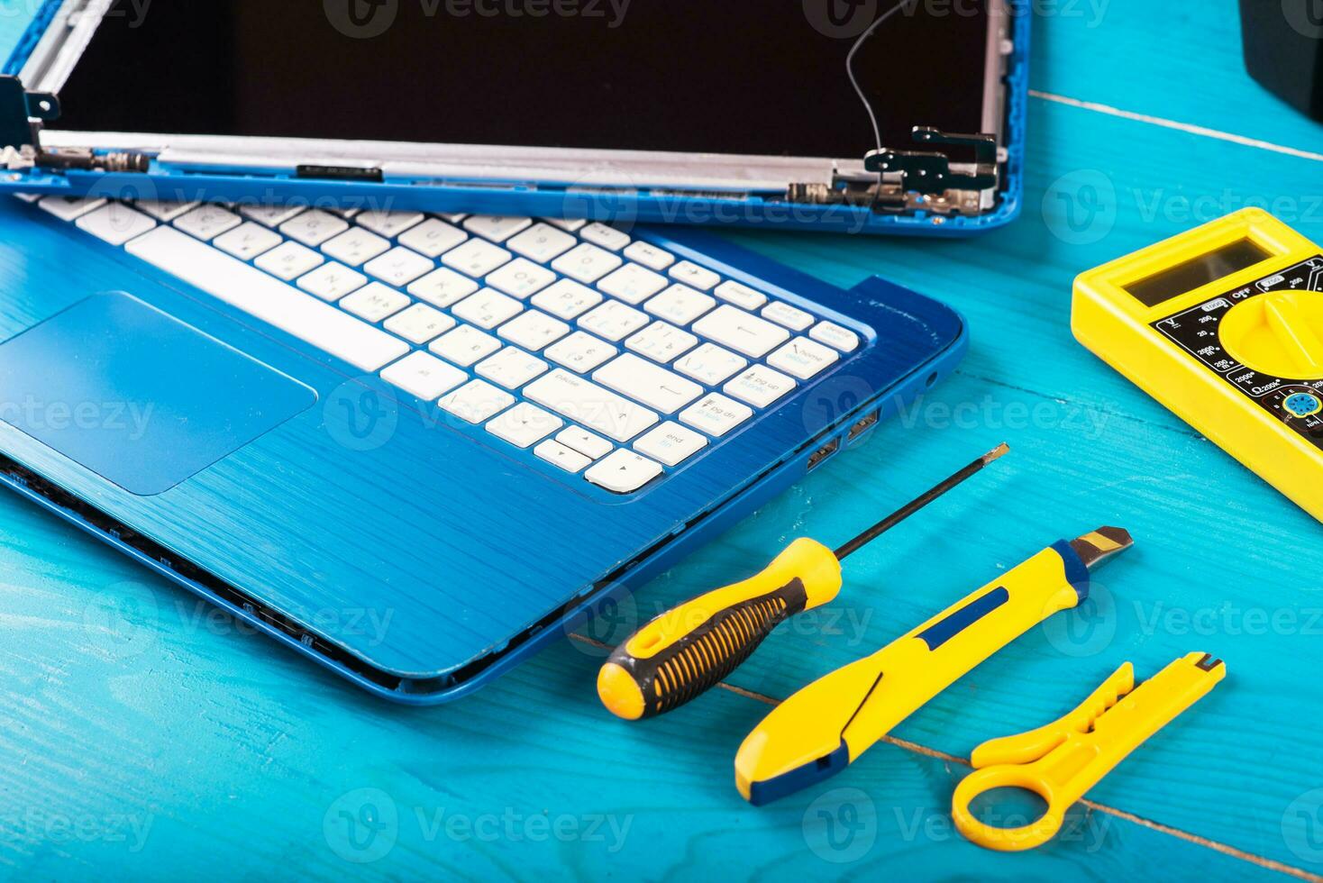 Wizard repairs laptop with tools and hands on the blue wooding table. top view photo