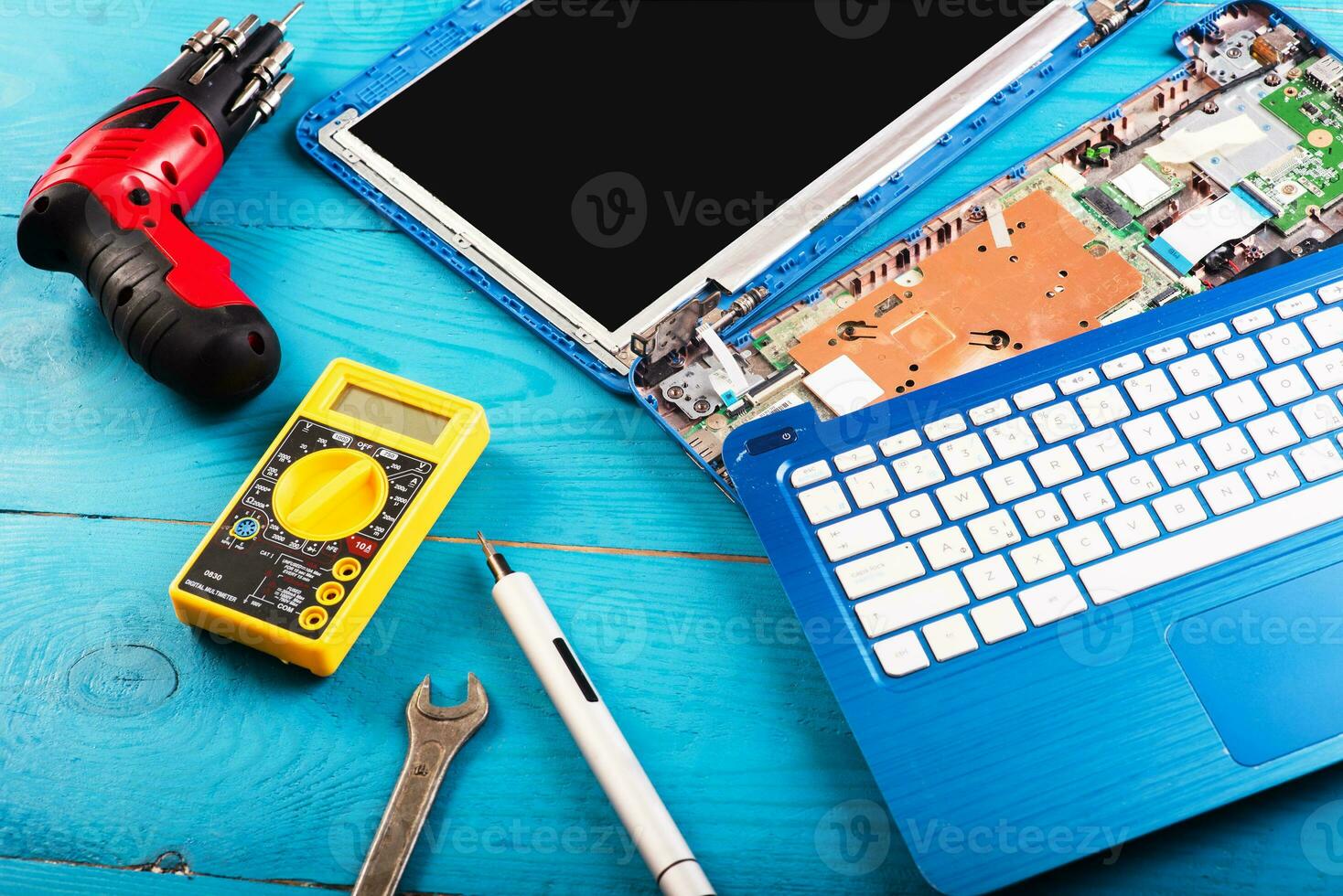 Wizard repairs laptop with tools and hands on the blue wooding table. top view photo