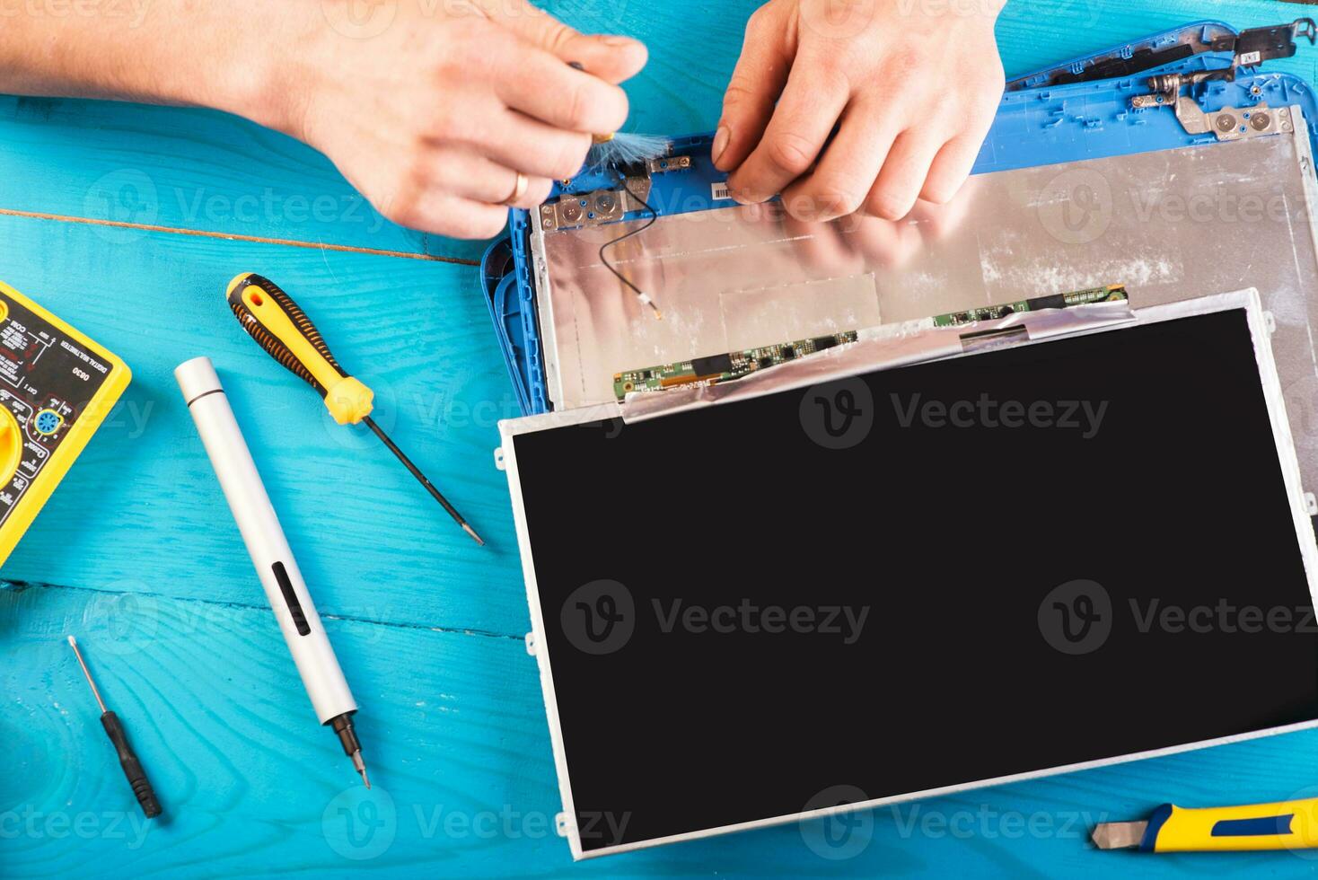 Wizard repairs laptop with tools and hands on the blue wooding table. top view photo