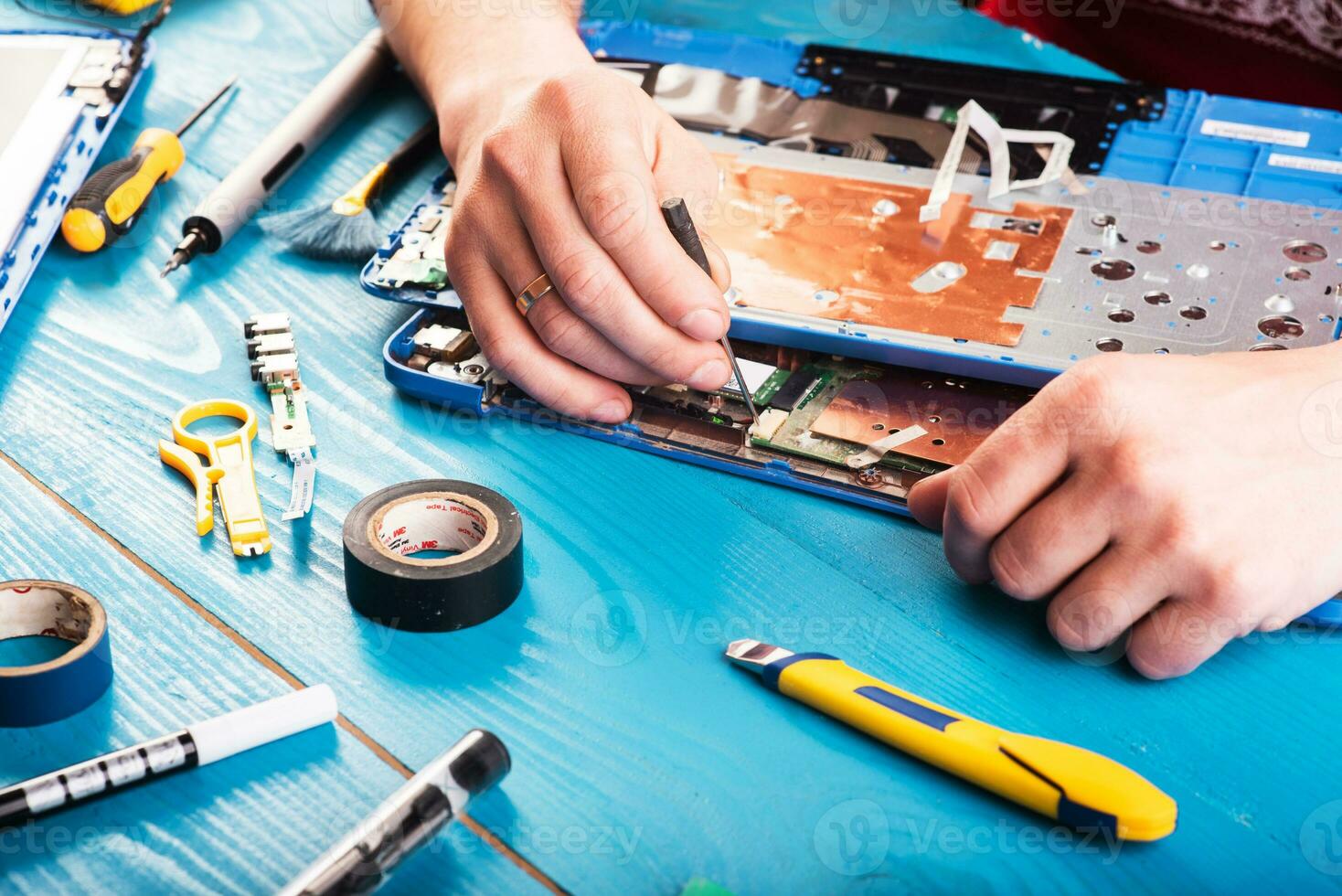 Wizard repairs laptop with tools and hands on the blue wooding table. top view photo