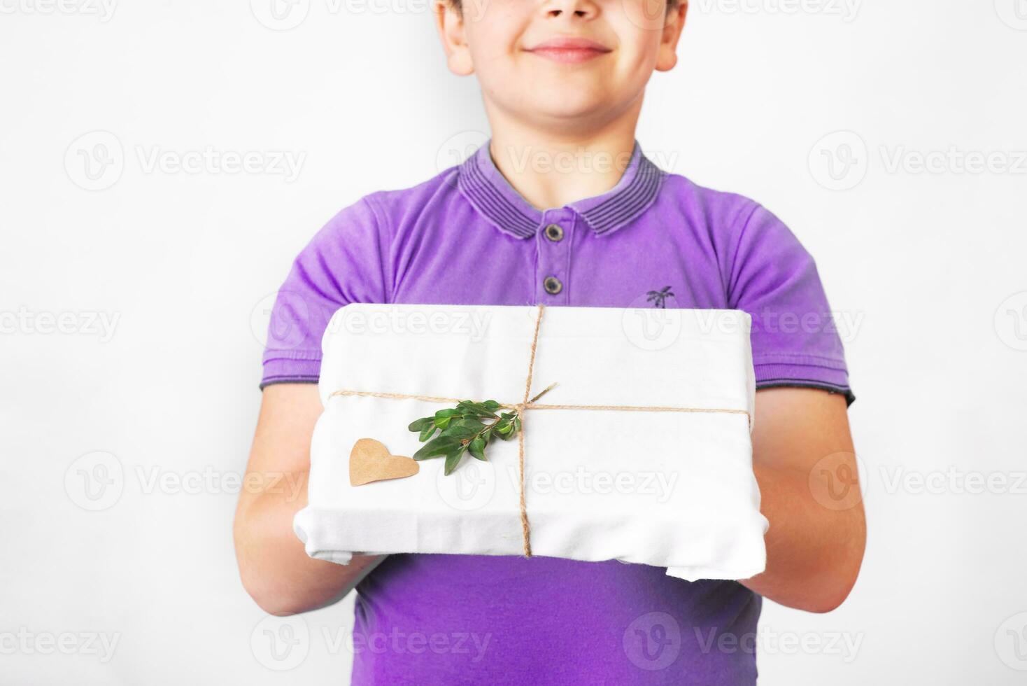retrato de un encantador linda chico en muy peri camiseta participación presente caja en tela embalaje. cero residuos concepto. de cerca foto
