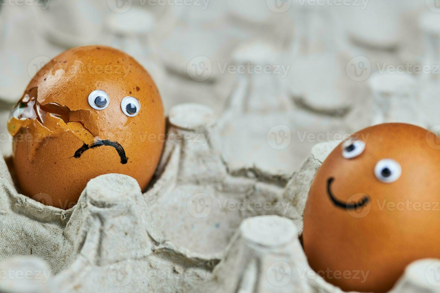 Funny egg and sad cracked egg in paper egg tray photo