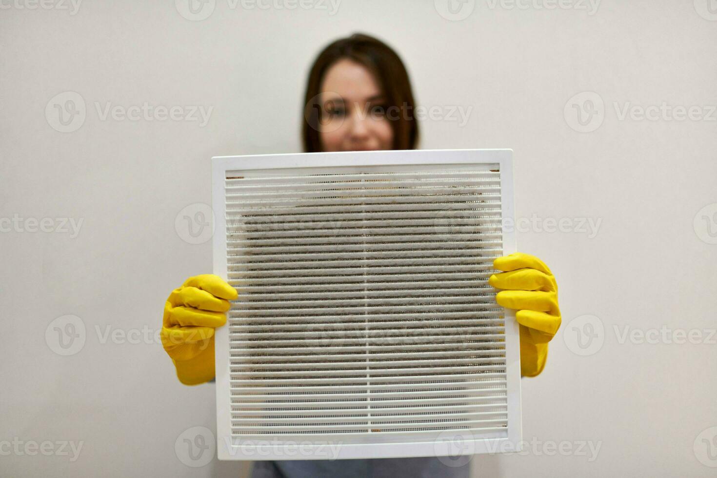 Woman holding dirty and dusty ventilation grille, blurred. photo