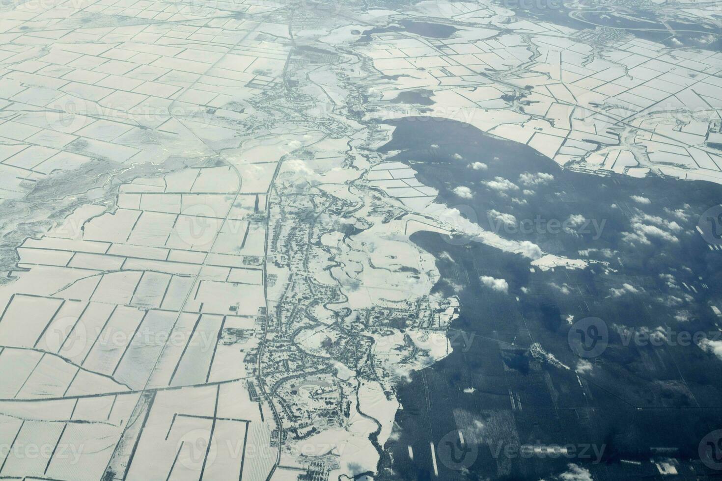 Aerial cloudscape view over clouds top to snow covered rivers, roads, cities and fields, winter air photo