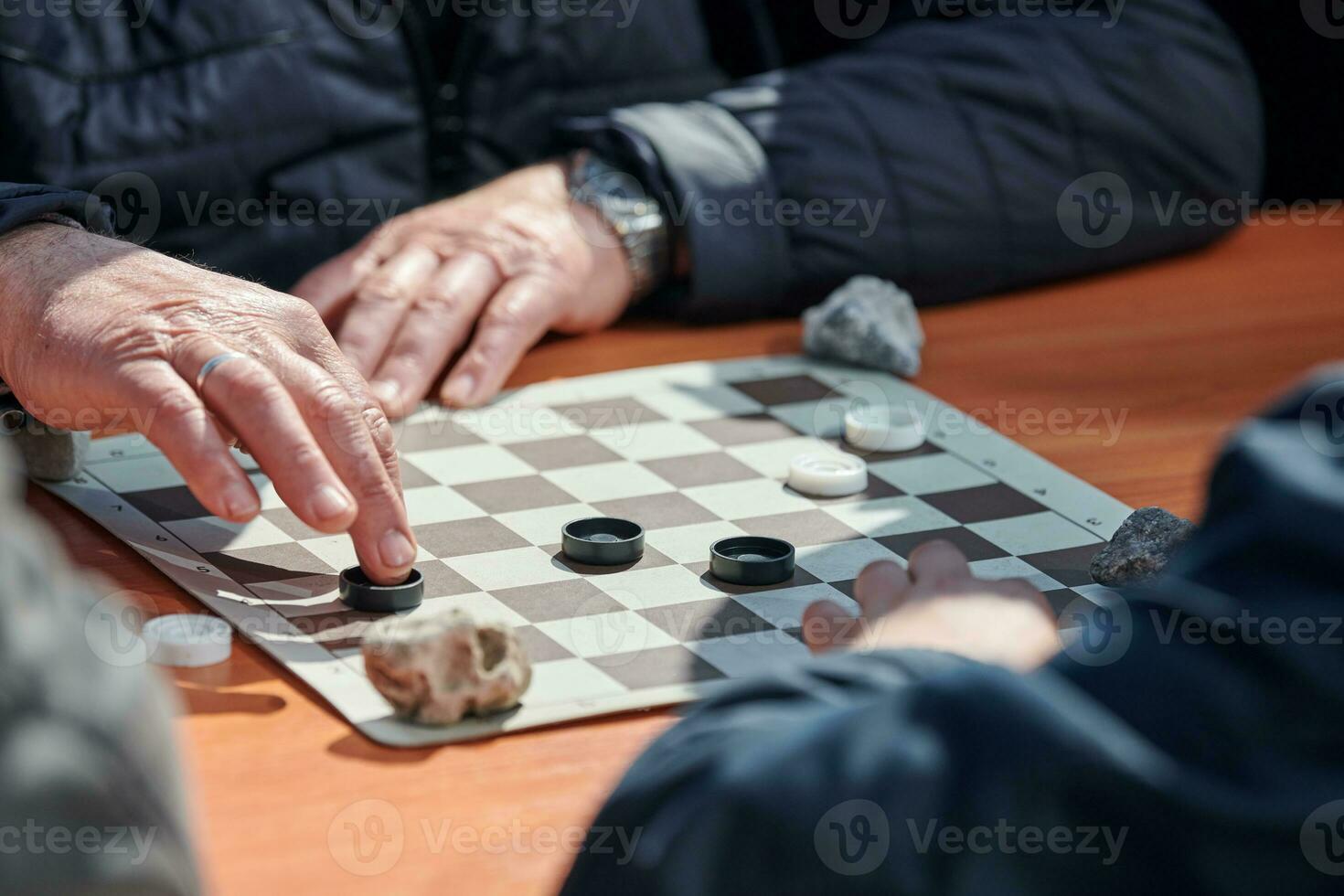 Outdoor checkers tournament on paper checkerboard on table, close up players hands photo