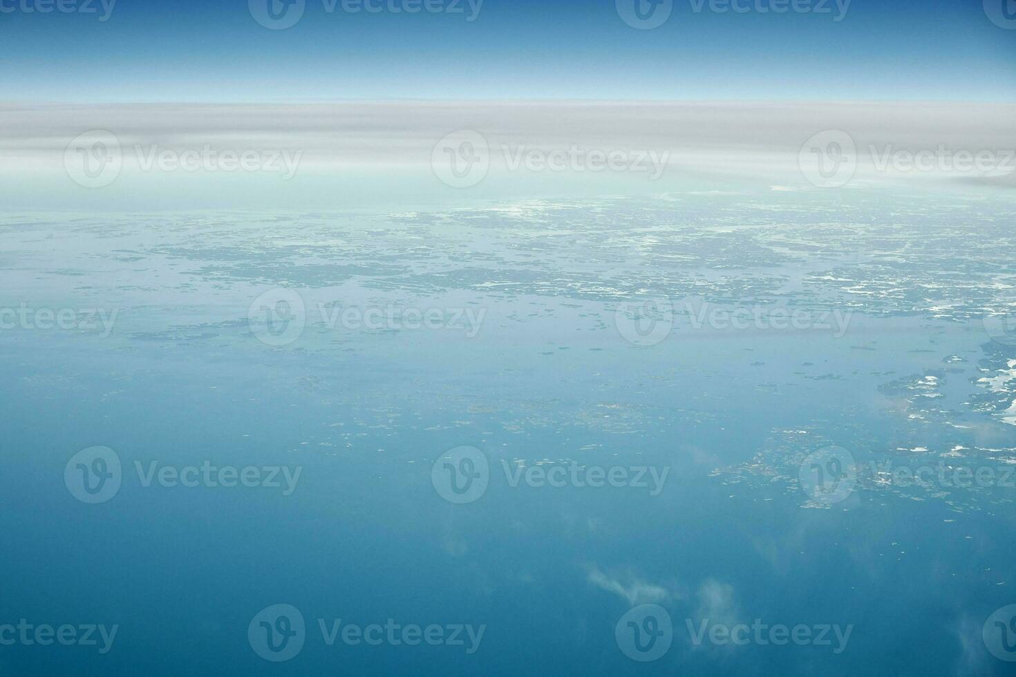 Aerial view from airplane window over clouds top to cold north sea, winter fresh frosty air photo