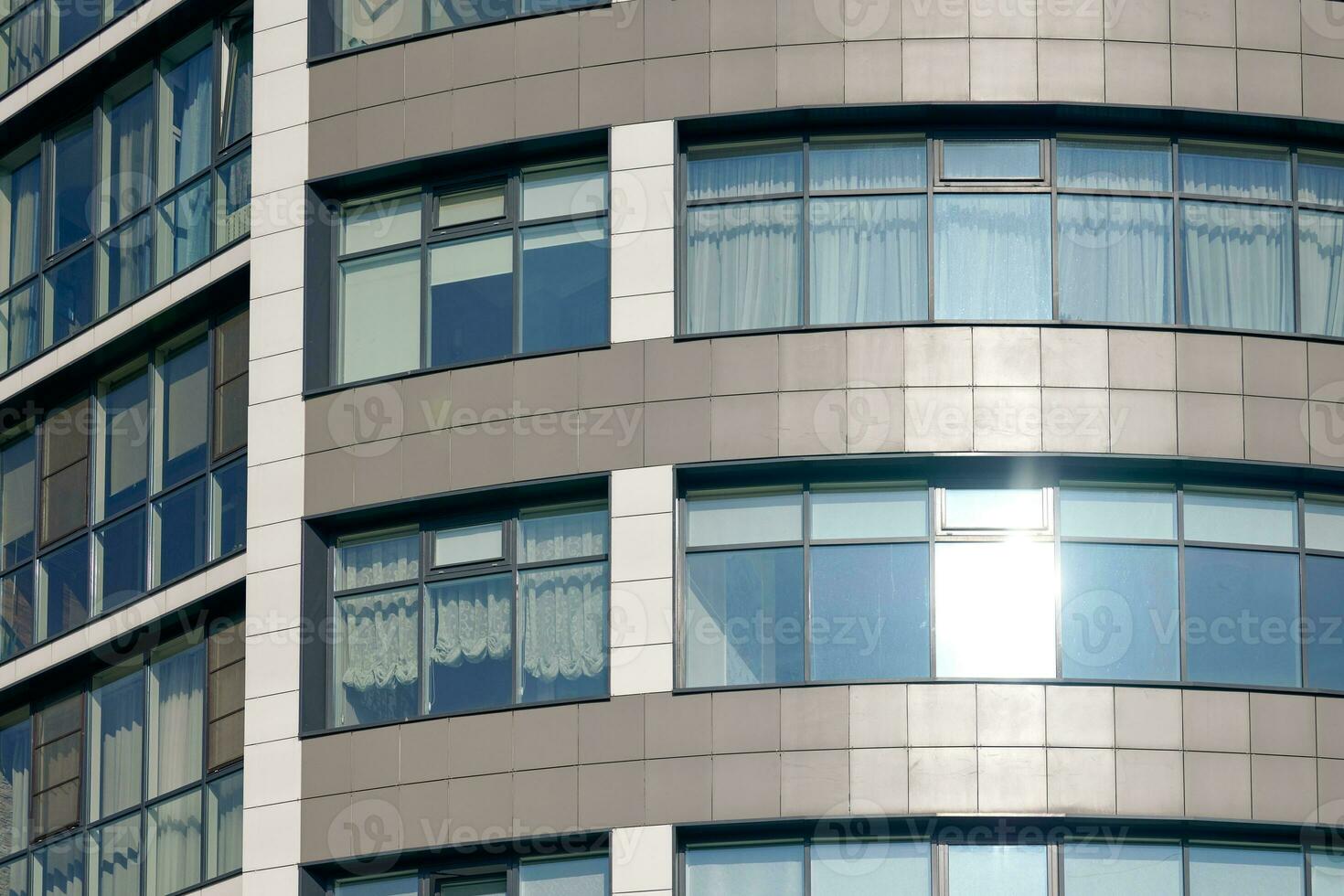 Close up view to office skyscraper windows, high business building windows with sunlight glare photo