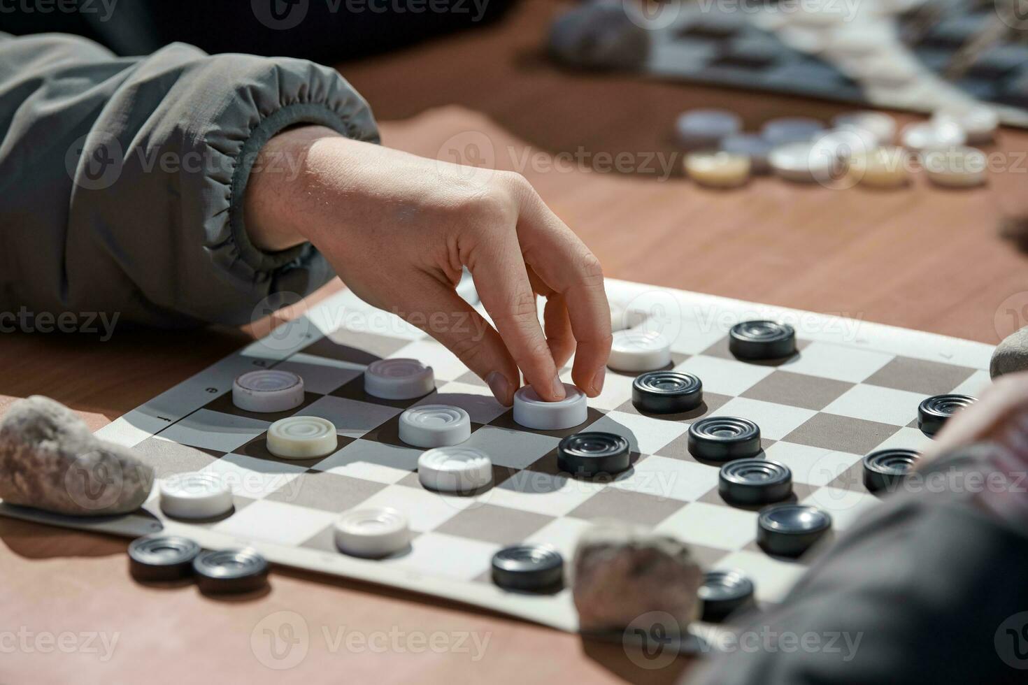 Outdoor draughts competition on paper checkerboard on table, close up players hands photo