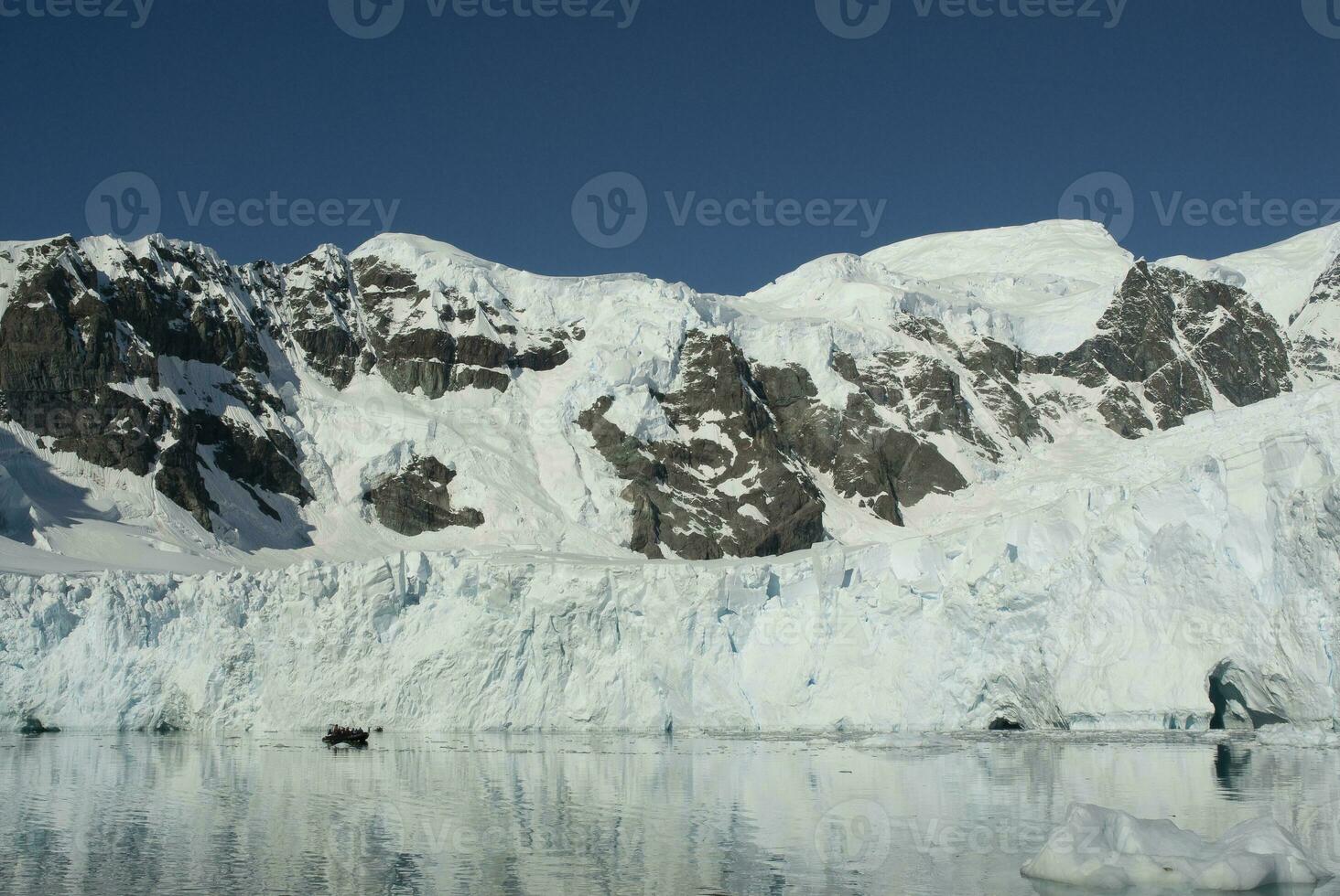 Tourists watching glaciers and mountains in Paradise bay, Antarctic peninsula, Antartica.. photo
