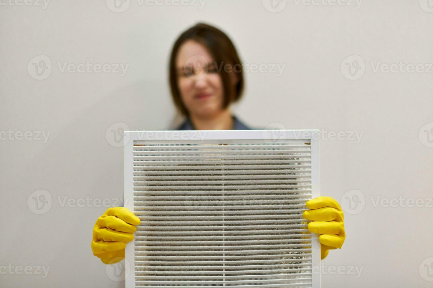 Woman holding dirty and dusty ventilation grille, disgusted photo