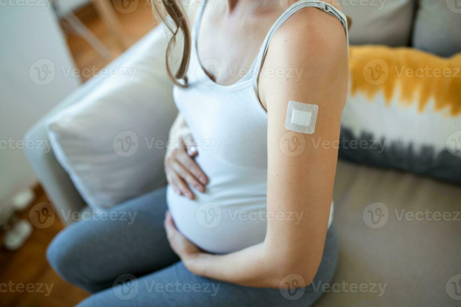 Adhesive bandage on arm after injection vaccine or medicine,ADHESIVE BANDAGES PLASTER - Medical Equipment,Soft focus Adhesive bandage on a Pregnant female brachium after covid-19 vaccination photo