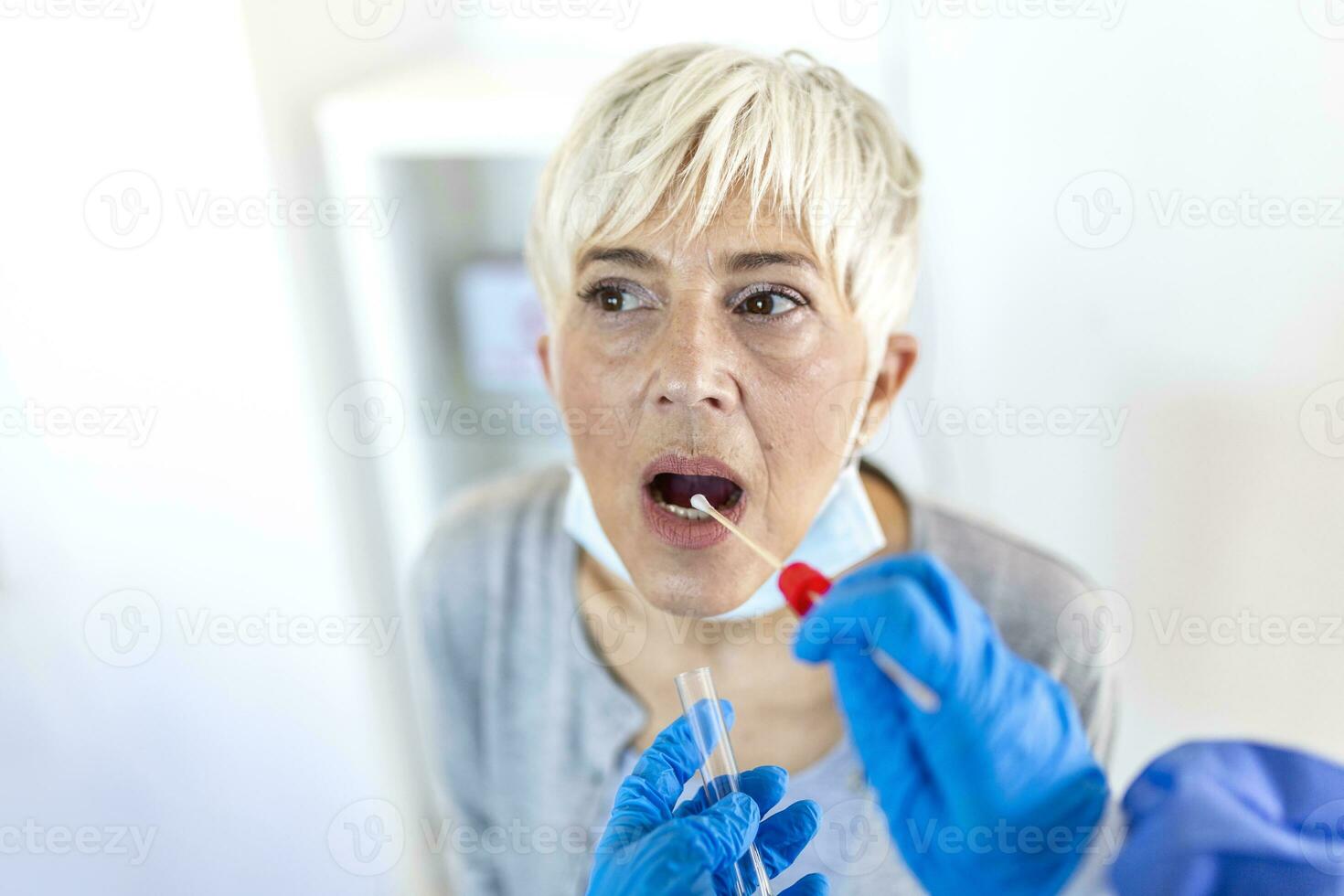 Physician wearing personal protective equipment performing a Coronavirus COVID-19 PCR test, patient nasal NP and oral OP swab sample specimen collection process, viral rt-PCR DNA diagnostic procedure photo