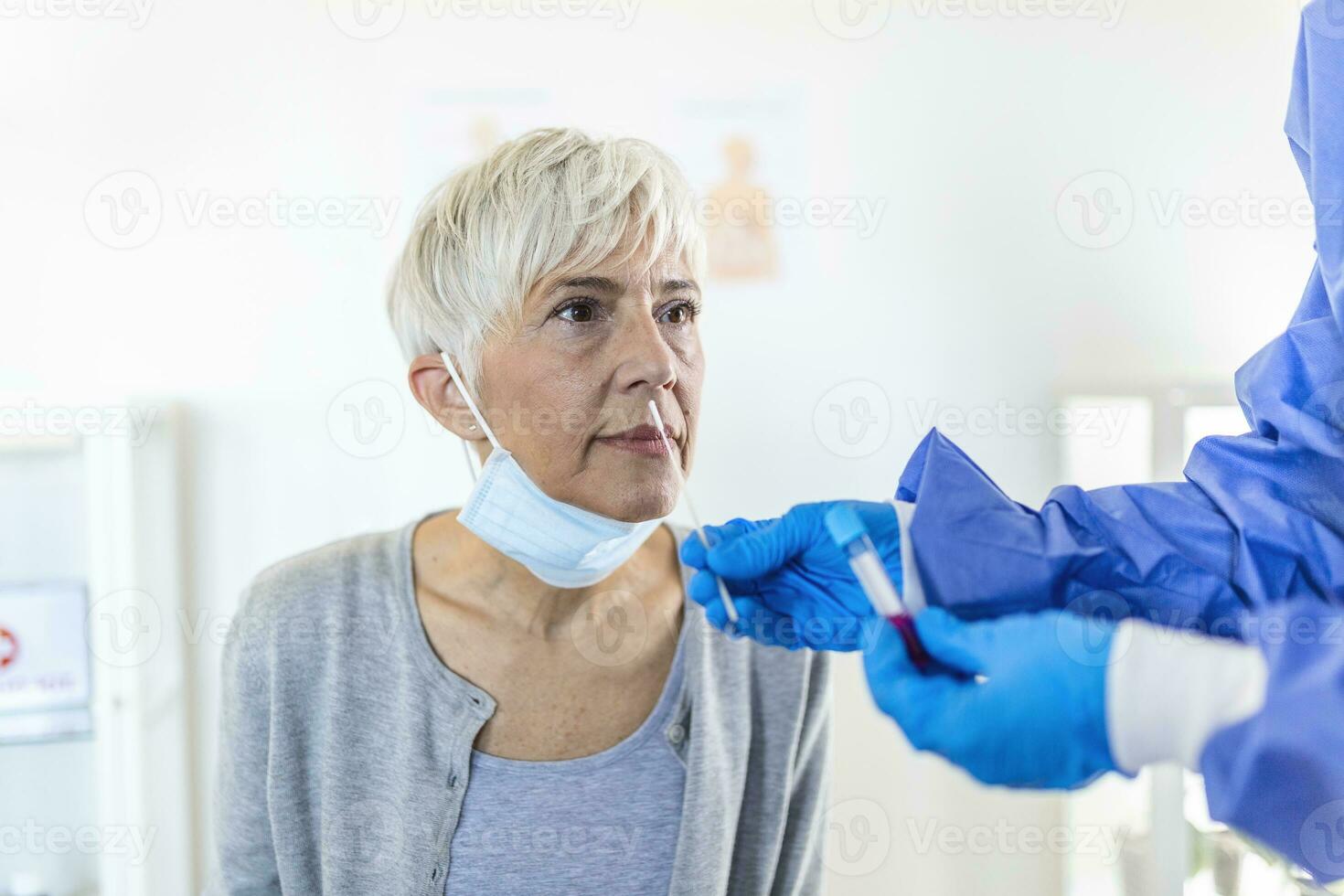 Physician wearing personal protective equipment performing a Coronavirus COVID-19 PCR test, patient nasal NP and oral OP swab sample specimen collection process, viral rt-PCR DNA diagnostic procedure photo