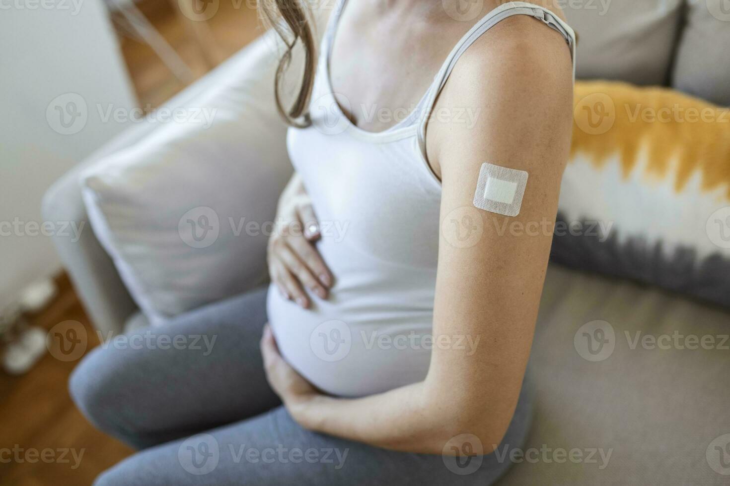 Coronavirus Vaccination During Pregnancy. Joyful Pregnant Lady Showing Vaccinated Arm With Plaster Strip Posing After Coronavirus Vaccine Injection. Corona Virus Immunization photo