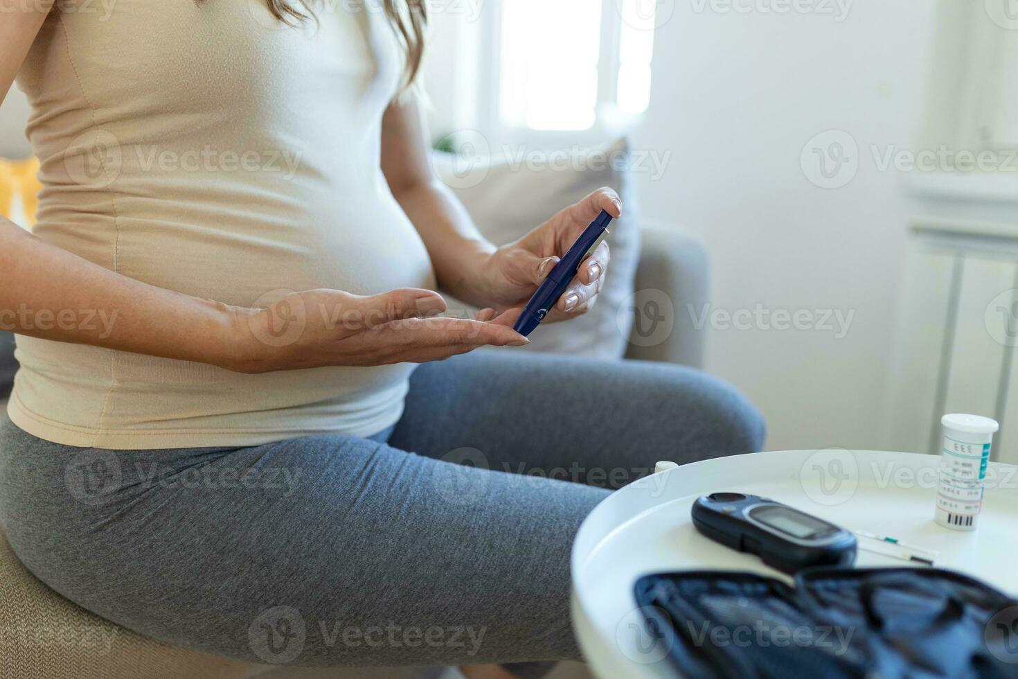 Blood sugar testing at home. Pregnant Woman Checking Blood Sugar Level At Home. Diabetic Checking Blood Sugar Levels. Pregnant Woman checking blood sugar level by glucometer and test stripe at home photo