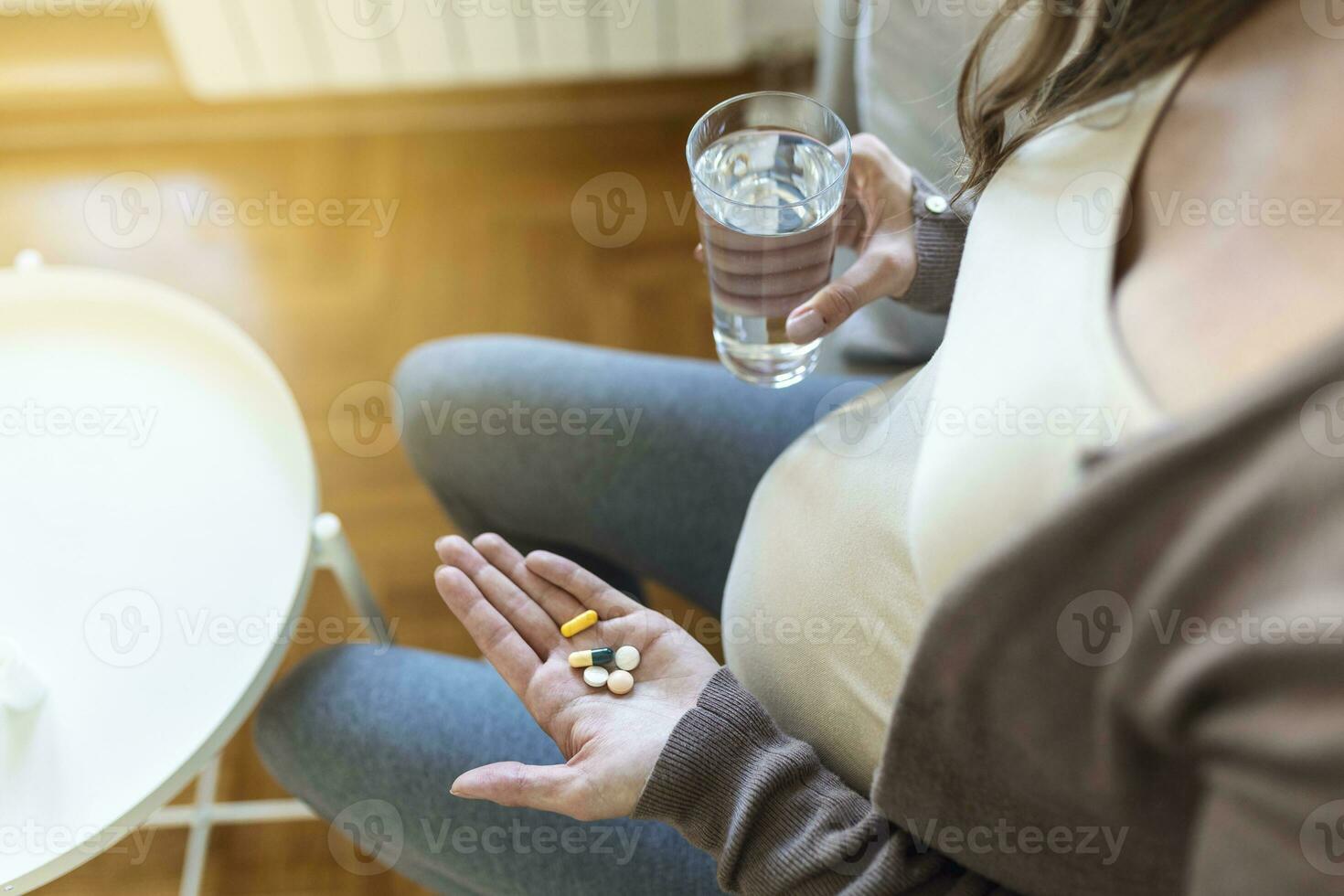 Cropped view of sick and ill pregnant woman holding different pills on palm hand, showing medical preparat on camera photo