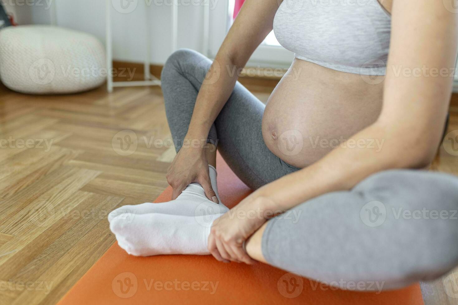 Closeup shot of an unrecognizable pregnant woman with her hands on her belly at home photo