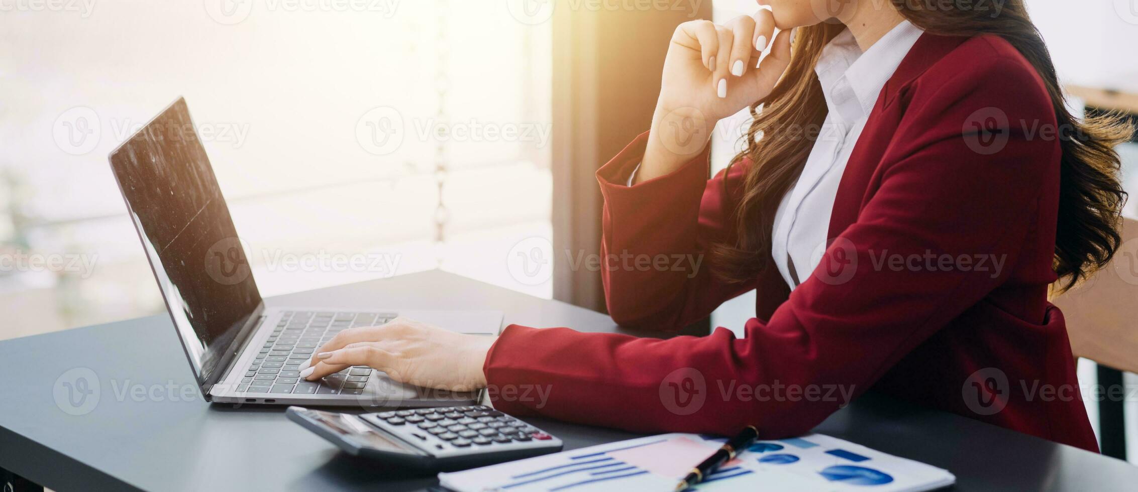 Asian Business woman using calculator and laptop for doing math finance on an office desk, tax, report, accounting, statistics, and analytical research concept photo