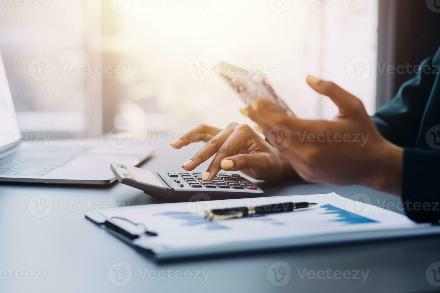 Asian Business woman using calculator and laptop for doing math finance on an office desk, tax, report, accounting, statistics, and analytical research concept photo