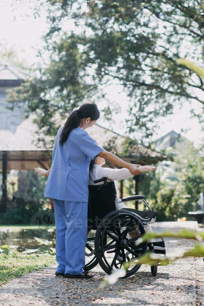 joven fisioterapeuta asiática que trabaja con una anciana caminando con un andador foto